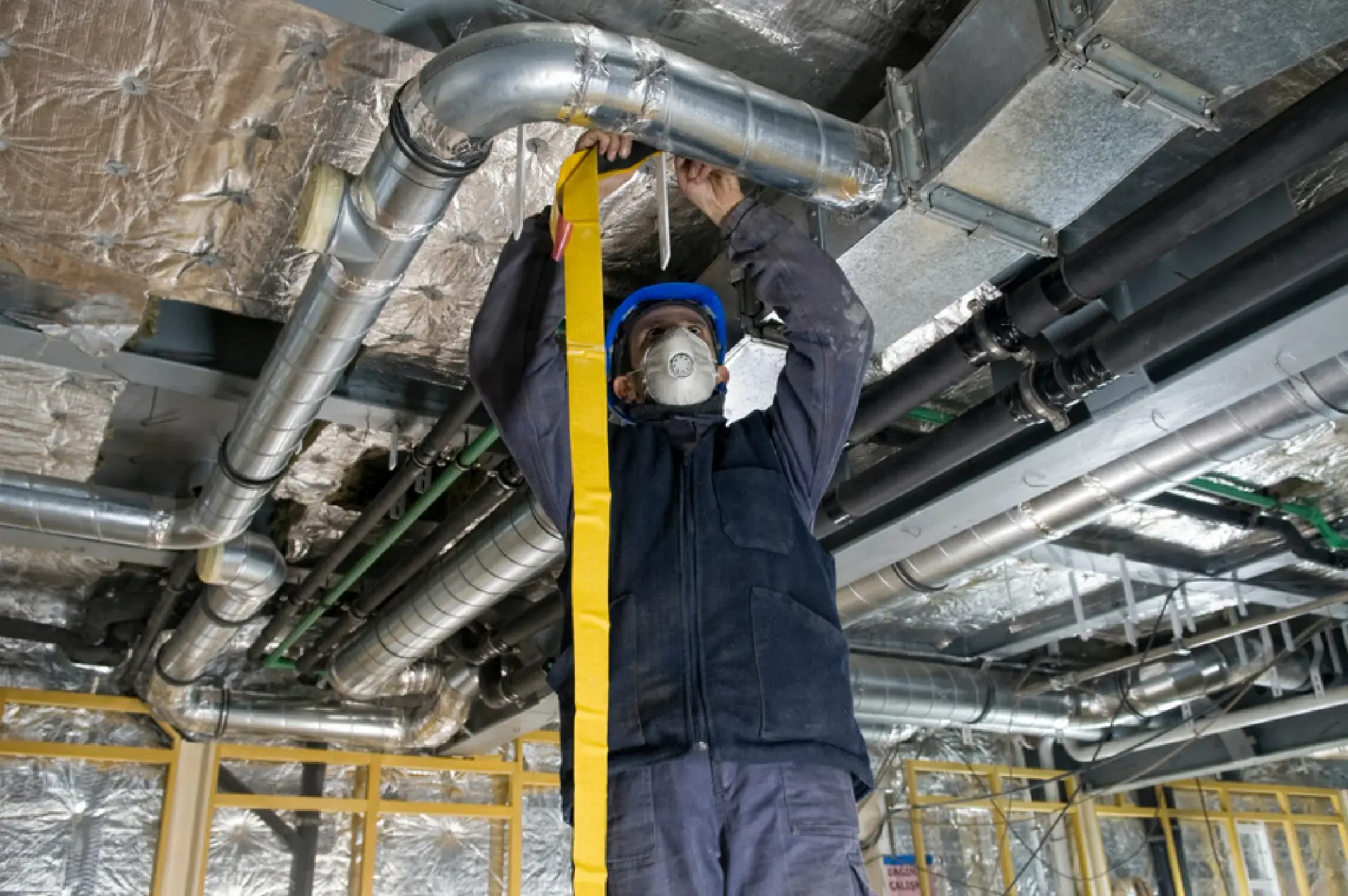 Technician working on ducting and mechanical services in a ceiling void