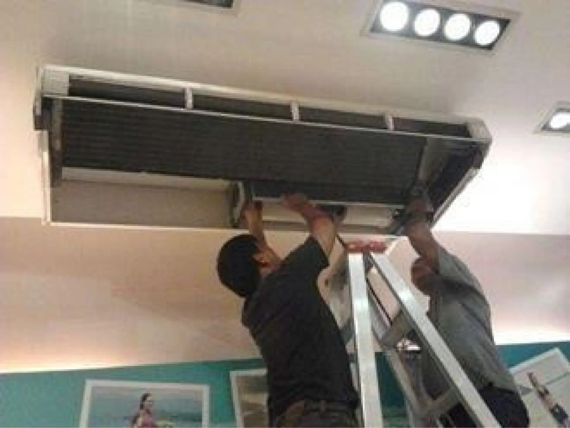 Technicians servicing a ceiling cassette air-conditioning unit